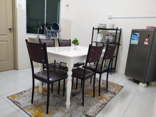 kuchnia ze stołem, krzesłami i lodówką w obiekcie WAFID HOMESTAY 2 SERI ISKANDAR w mieście Seri Iskandar