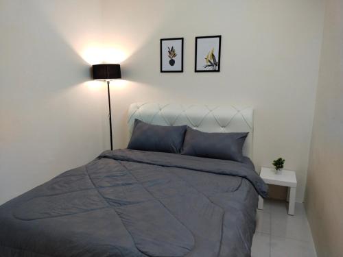 a bedroom with a bed with a blue comforter and a lamp at WAFID HOMESTAY 2 SERI ISKANDAR in Seri Iskandar