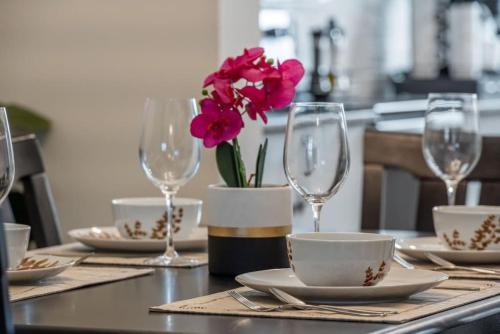 a table with plates and glasses and flowers on it at Extra Large House with AC, Banff Access, Sleep 12, BBQ, 4 Bedrooms & 2 Sleeper Sofa Beds in Airdrie
