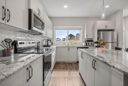 a kitchen with white cabinets and a counter top at Newly Built Family Townhome, Sleeps 12 Comfortably in Airdrie