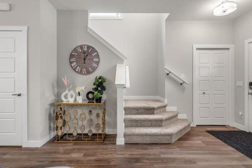 a hallway with a clock on the wall and stairs at Extra Large House with AC, Banff Access, Sleep 12, BBQ, 4 Bedrooms & 2 Sleeper Sofa Beds in Airdrie