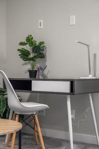 a black desk with a chair and a plant at Extra Large House with AC, Banff Access, Sleep 12, BBQ, 4 Bedrooms & 2 Sleeper Sofa Beds in Airdrie