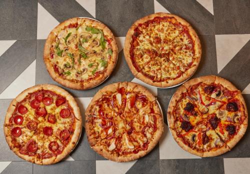 a group of four pizzas sitting on a table at Super 8 by Wyndham Chester East in Chester