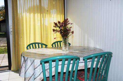 a table with chairs and a vase of flowers on it at Mimosas in Morcenx