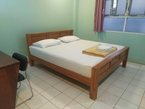 um quarto com uma cama com lençóis brancos e uma secretária em โรงแรมพรถวิล ศรีสะเกษ Sisaket PonTaWin Budget Inn em Si Sa Ket