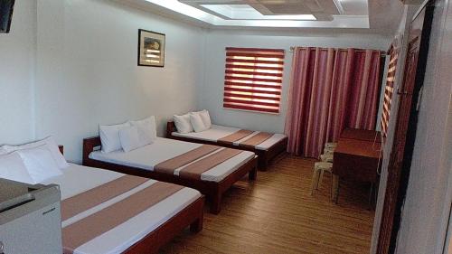 um quarto com duas camas e uma mesa e uma janela em FNT Transient House em Alaminos