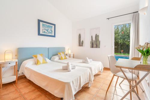 1 dormitorio con 2 camas y mesa en Villa Libra, en Cala en Forcat