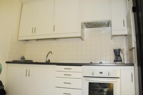 eine Küche mit weißen Schränken und einem Waschbecken in der Unterkunft Arbousiers in Morcenx