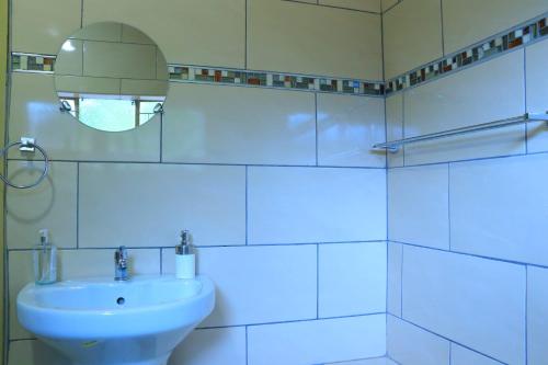 a white bathroom with a sink and a mirror at La Maison Guesthouse in Thohoyandou