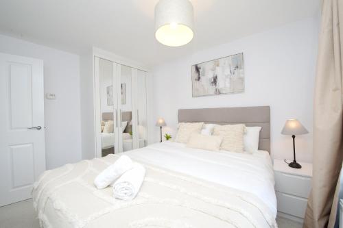 um quarto branco com uma grande cama branca com almofadas brancas em Fairfields Coach House em Stony Stratford