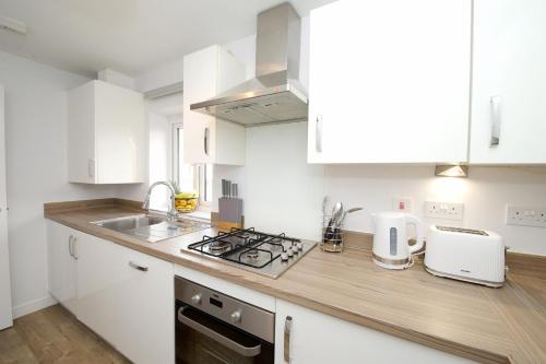 a kitchen with white cabinets and a counter top at Fairfields Coach House in Stony Stratford