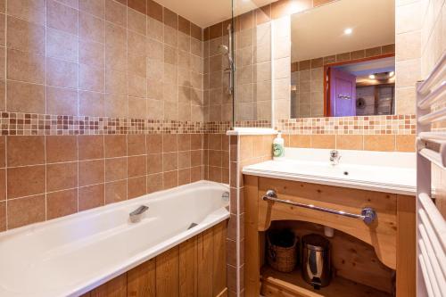 ein Badezimmer mit Badewanne und Waschbecken in der Unterkunft L'Ours des Alpages - 301C - Piscine partagée in Villarembert
