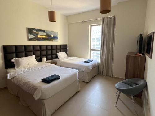 um quarto de hotel com duas camas e uma televisão em CozyNest - 3br Beachfront apt, JBR em Dubai