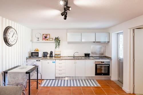 a kitchen with white cabinets and a clock on the wall at Gaia Elegant Retreat I in Canidelo