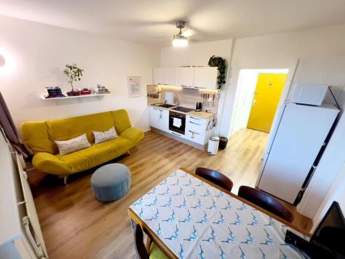 a living room with a yellow couch and a kitchen at Yellow Sofa FREE PARKING Place in Bratislava