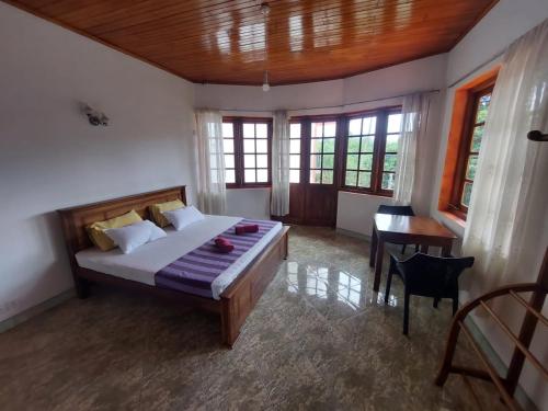 a bedroom with a bed and a desk and windows at Mystique Hideout in Kandy