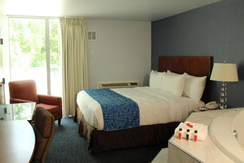 a hotel room with a bed and a chair at Travelodge by Wyndham Water's Edge Hotel - Racine in Racine