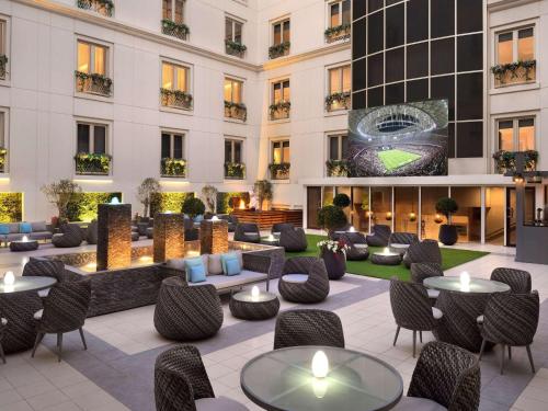 Mövenpick Hotel & Apartments Bur Dubai في دبي: صورة لوبي الفندق مع الطاولات والكراسي
