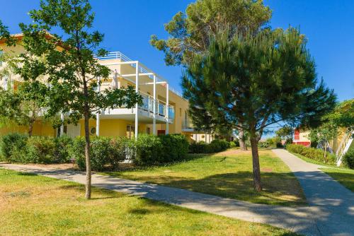 a yellow building with trees in front of it at Lagrange Vacances Les Terrasses des Embiez in Six-Fours-les-Plages