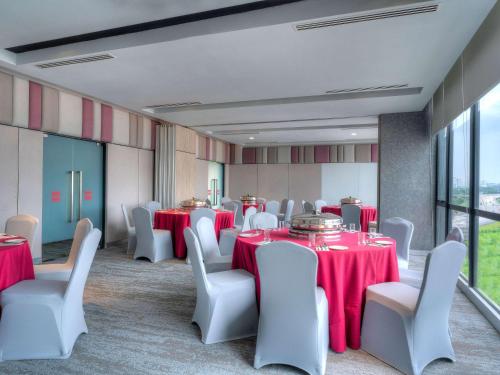 a room with tables and white chairs with red table cloth at ibis PJCC Petaling Jaya in Petaling Jaya