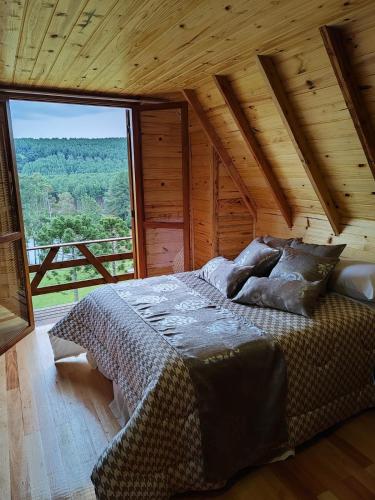a bed in a room with a large window at Cabana Santa Cruz in São Francisco de Paula