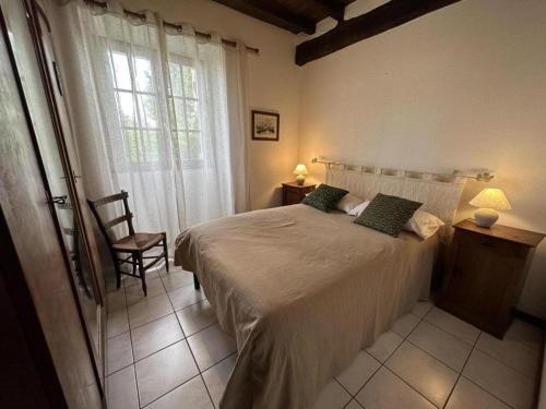 a bedroom with a bed and a chair and a window at Chez michou ii in Horsarrieu