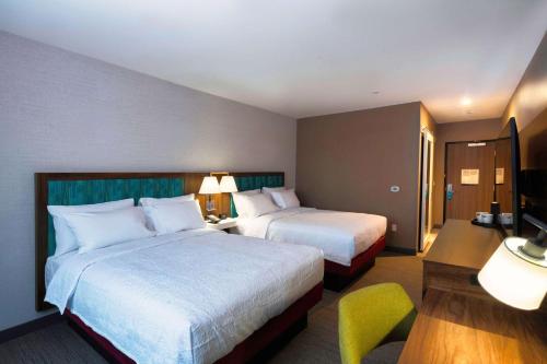 a hotel room with two beds and a desk at Hampton Inn Needles in Needles