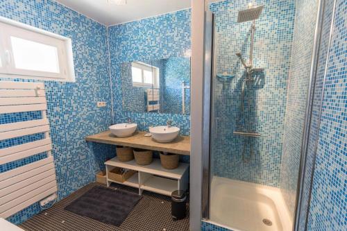 baño de azulejos azules con 2 lavabos y ducha en Gite caperot, en Eyrès - Moncube