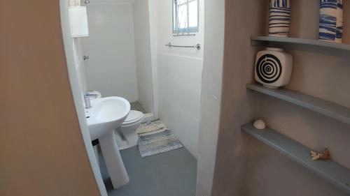 a white bathroom with a sink and a toilet at The Beach Bungalows in Zinkwazi Beach