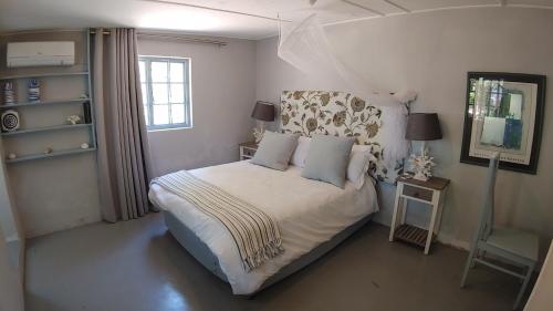 a bedroom with a bed with white sheets and blue pillows at The Beach Bungalows in Zinkwazi Beach