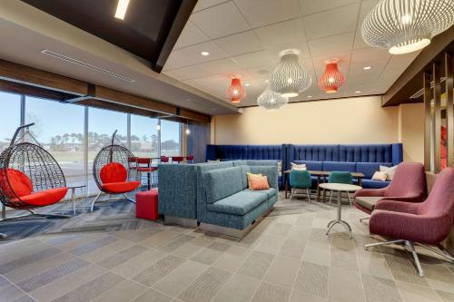 a waiting room with chairs and tables and windows at Tru By Hilton Leland Wilmington in Leland