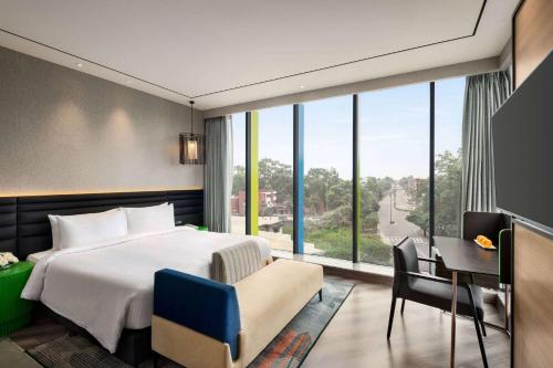 a bedroom with a bed and a desk and a window at Ramada Encore by Wyndham Bareilly Civil Lines in Bareilly