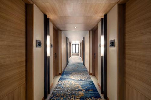 a long hallway with a blue carpet and wooden ceilings at Ramada Encore by Wyndham Bareilly Civil Lines in Bareilly