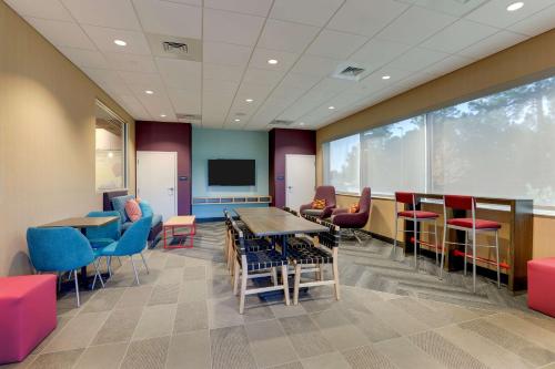 a waiting room with tables and chairs and a tv at Tru By Hilton Leland Wilmington in Leland
