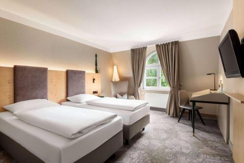 a hotel room with two beds and a desk at Vienna House Easy by Wyndham Castrop-Rauxel in Castrop-Rauxel