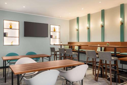 a conference room with tables and chairs and a tv at Vienna House Easy by Wyndham Castrop-Rauxel in Castrop-Rauxel