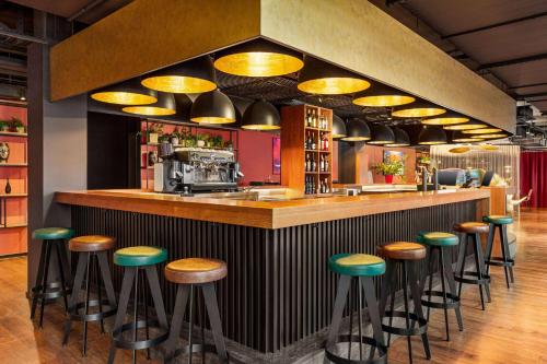 a bar with green stools in a restaurant at Amedia Munich Dachau, Trademark Collection by Wyndham in Dachau