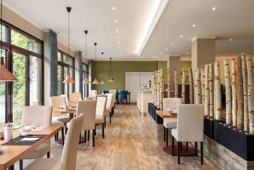 a restaurant with tables and chairs and windows at Amedia Hotel Siegen City, Trademark Collection by Wyndham in Siegen