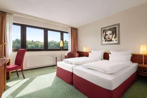 a hotel room with two beds and a window at Amedia Siegen, Trademark Collection by Wyndham in Siegen
