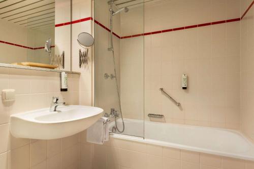 a bathroom with a sink and a shower and a tub at Amedia Hotel Siegen City, Trademark Collection by Wyndham in Siegen