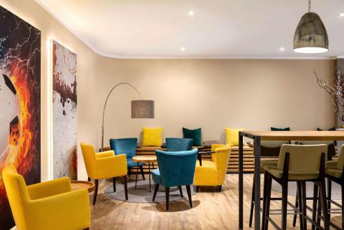 a dining room with colorful chairs and a table at Amedia Hotel Siegen City, Trademark Collection by Wyndham in Siegen
