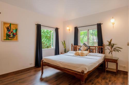 a bedroom with a bed and two windows at The Bumblebee- Serene 3BHK Villa- Candolim, Goa By StayMonkey in Candolim