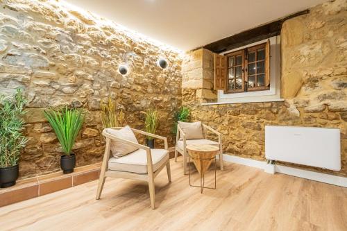 a room with a stone wall with two chairs and a tv at Hotel BESTPRICE Santillana in Santillana del Mar