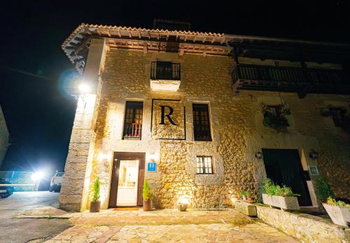a stone building with the r on it at night at Hotel BESTPRICE Santillana in Santillana del Mar