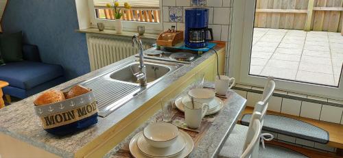 a kitchen with a sink and a table with dishes at Nordsee Ferienwohnung Nord in Dornumersiel