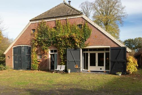 an old brick house with a bench in front of it at De Lindenhoeve in Valthe