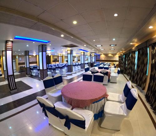 un salón de banquetes con mesa redonda y sillas blancas en Hotel Corporate Inn, Patna, en Khagaul