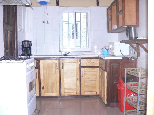 a kitchen with wooden cabinets and a window at Fayes Apartments in Brusubi