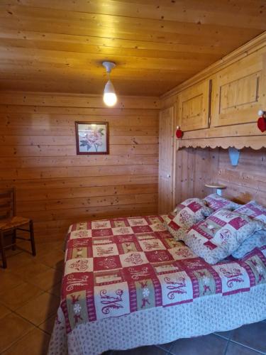 um quarto com uma cama num chalé de madeira em Pierre de Famille em Manigod