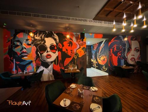 a restaurant with tables and a large painting on the wall at The Kannelite in Jamshedpur